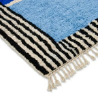 Détail tapis berbère bleu avec bordures rayées noires et blanches et franges finition artisanale haut de gamme