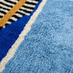 Gros plan tapis berbère bleu avec motifs géométriques multicolores design moderne artisanal marocain