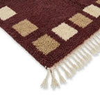 Détail tapis berbère bordeaux avec carrés beige et franges finition artisanale marocaine haut de gamme