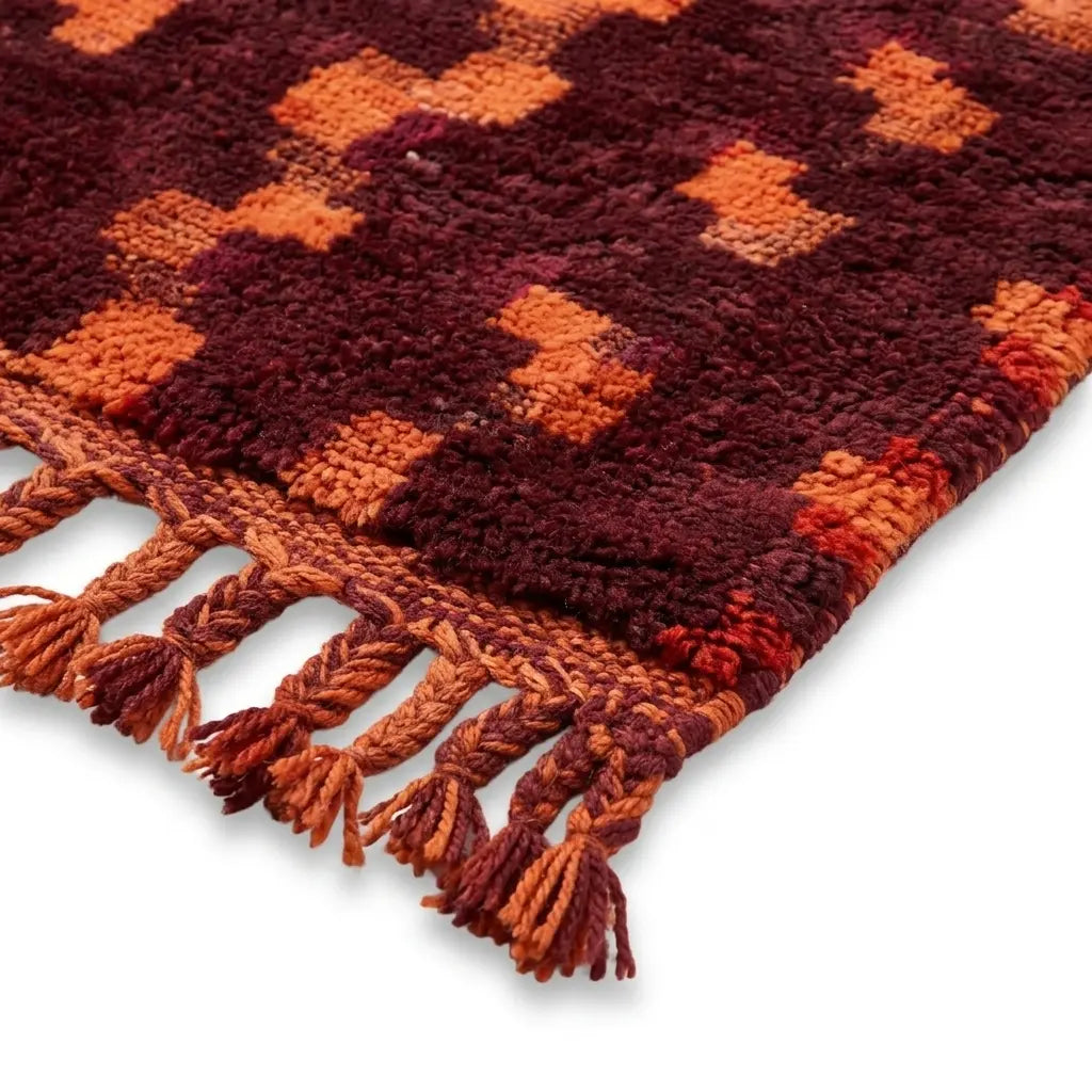 détail franges tressées sur tapis berbère bordeaux et orange avec motifs ethniques, style bohème chic