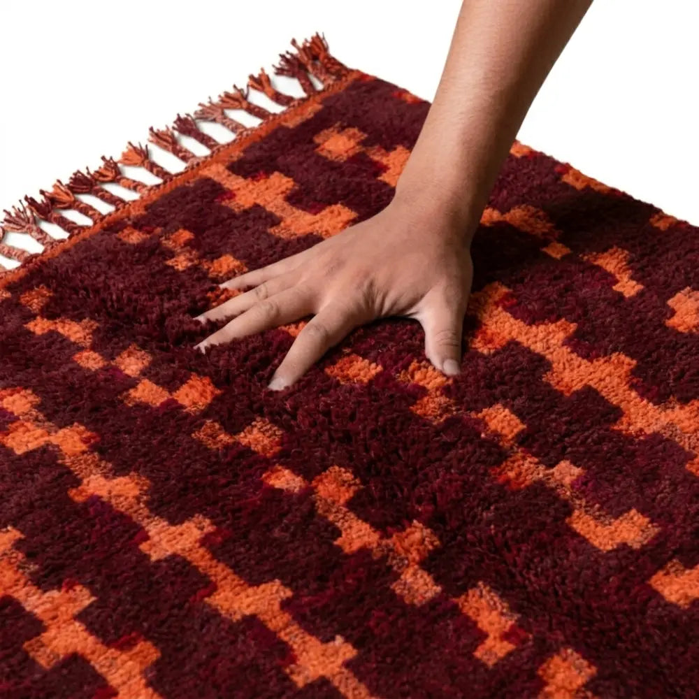 main enfoncée dans tapis berbère bordeaux et orange ultra doux, fibres épaisses pour confort premium