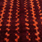 gros plan sur tapis berbère bordeaux avec motifs ethniques orange, texture dense et finition artisanale haut de gamme