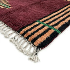 Détail tapis berbère bordeaux avec rayures noires beige et franges finition artisanale marocaine haut de gamme