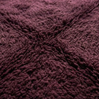 Gros plan tapis berbère bordeaux texture laine épaisse moelleuse qualité artisanale marocaine