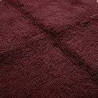 Gros plan tapis berbère bordeaux texture laine épaisse moelleuse artisanat marocain premium