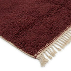 Détail tapis berbère bordeaux avec franges finition artisanale marocaine premium qualité supérieure