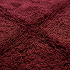 Gros plan tapis berbère bordeaux texture laine épaisse moelleuse artisanat marocain haut de gamme