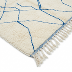 Détail tapis berbère crème avec lignes bleues et franges finition artisanale marocaine haut de gamme