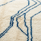 Gros plan tapis berbère crème avec lignes bleues motifs abstraits texture laine épaisse artisanat marocain