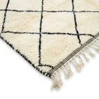 Détail tapis berbère crème avec lignes noires et franges finition artisanale marocaine haut de gamme