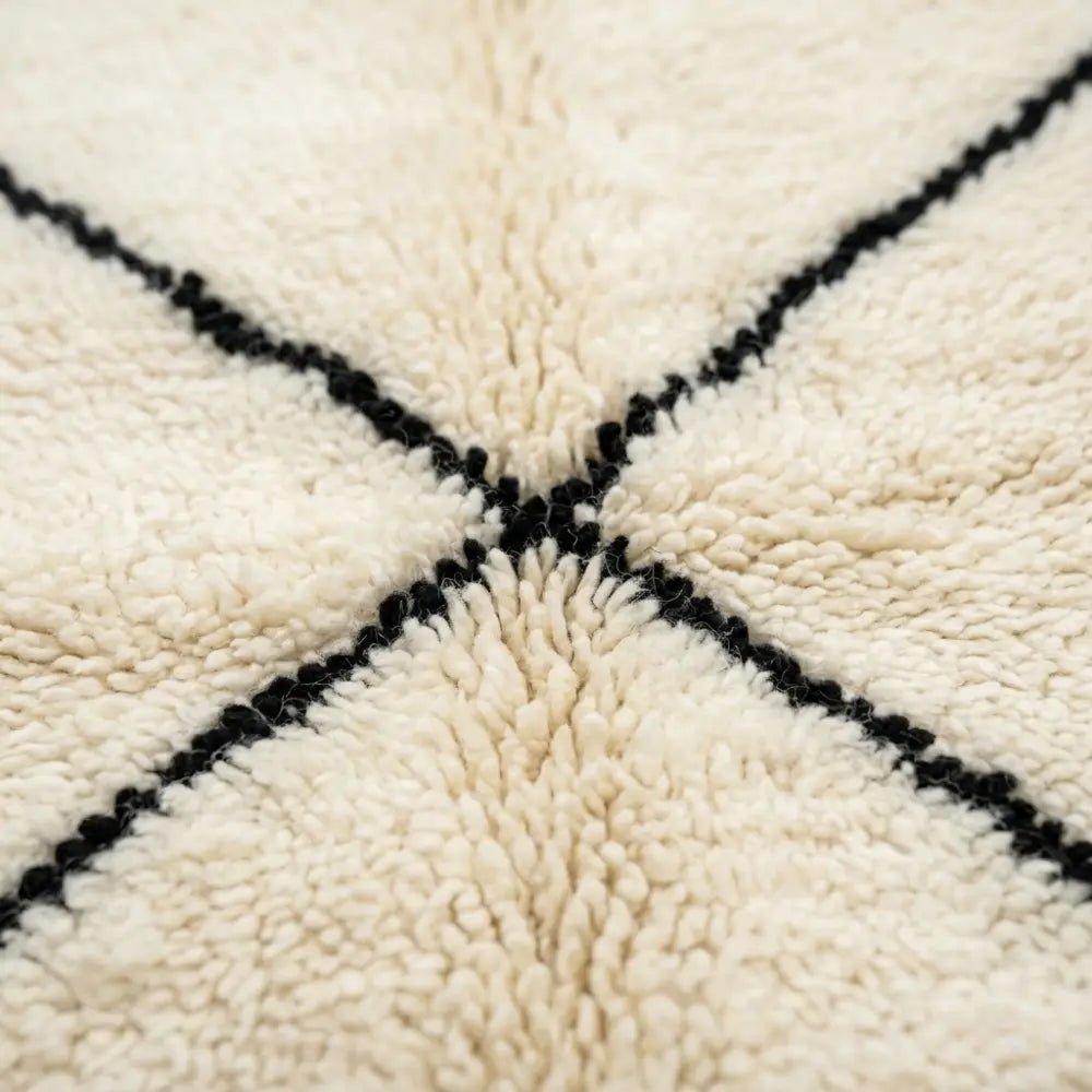 Gros plan tapis berbère crème avec motifs lignes noires texture laine épaisse artisanat marocain