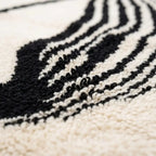 Gros plan tapis berbère crème et noir en laine épaisse texture douce artisanat marocain haut de gamme