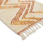 Détail tapis berbère crème avec motifs orange et franges finition artisanale marocaine haut de gamme
