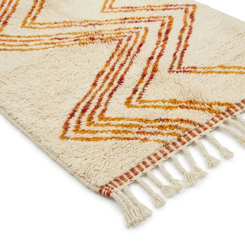 Détail tapis berbère crème avec motifs orange et franges finition artisanale marocaine haut de gamme