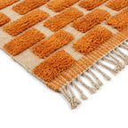 Détail tapis berbère crème avec motifs orange et franges finition artisanale marocaine haut de gamme