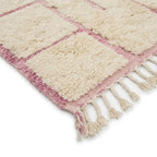 Détail tapis berbère crème avec lignes roses et franges finition artisanale marocaine haut de gamme