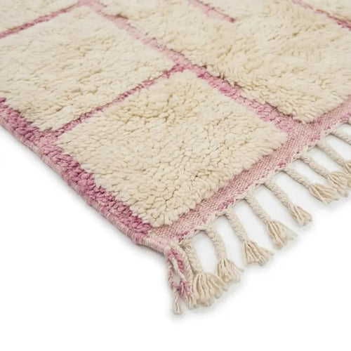 Détail tapis berbère crème avec lignes roses et franges finition artisanale marocaine haut de gamme