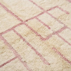 Gros plan tapis berbère crème avec motifs géométriques roses texture laine moelleuse design artisanal