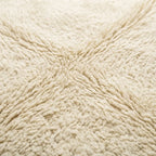 Gros plan tapis berbère crème uni texture laine épaisse moelleuse design artisanal marocain premium