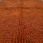 Gros plan sur texture tapis berbère ocre naturel, finition artisanale et toucher doux premium