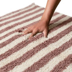 Gros plan sur tapis berbère en laine épaisse à rayures rose et beige, texture moelleuse et confortable haut de gamme