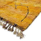 Détail des franges d’un tapis berbère artisanal marocain en laine jaune finition traditionnelle haut de gamme