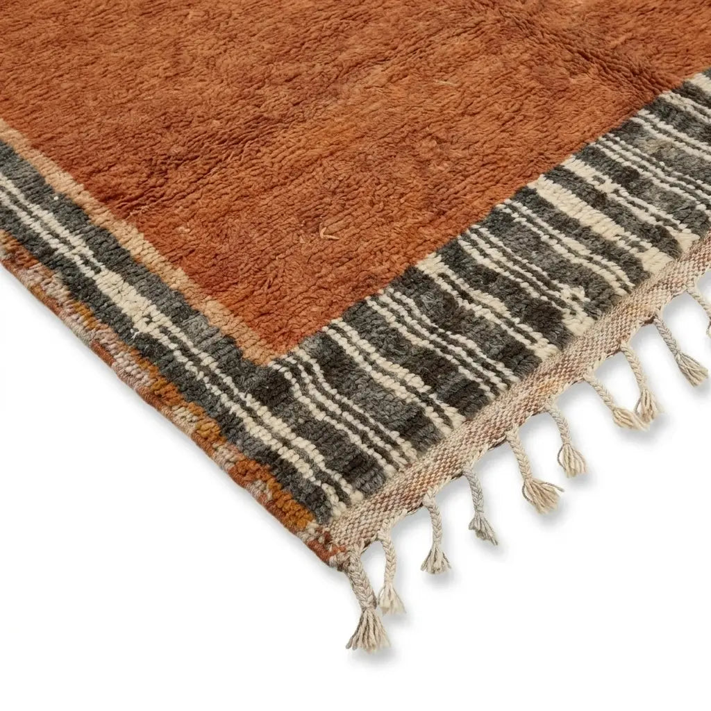 Détail tapis berbère avec franges et bordure rayée noir et beige, style authentique et finition artisanale