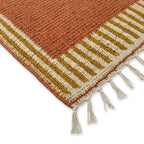 Détail tapis berbère avec franges et bordure rayée ocre et beige, style authentique et finition artisanale