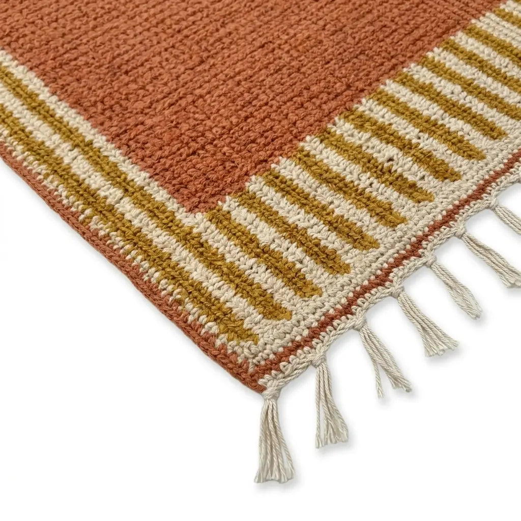 Détail tapis berbère avec franges et bordure rayée ocre et beige, style authentique et finition artisanale