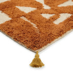 Détail coin tapis berbère avec franges et motifs ocre et écru, finition artisanale et design tendance