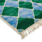 détail tapis berbère avec franges et motifs losanges vert bleu, finition artisanale en laine pour décoration authentique