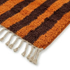 Détail tapis berbère avec franges tressées et rayures orange et marron, style authentique et qualité artisanale