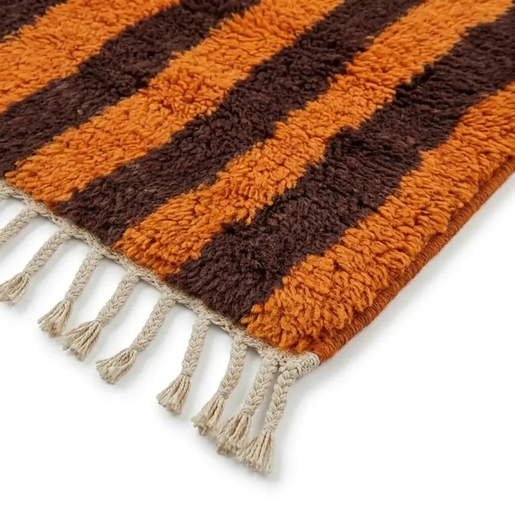 Détail tapis berbère avec franges tressées et rayures orange et marron, style authentique et qualité artisanale