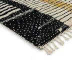 Détail tapis berbère géométrique noir et beige avec franges, style moderne et motifs abstraits tendance