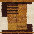 Gros plan sur motifs géométriques ocre et bruns d’un tapis berbère en laine artisanale