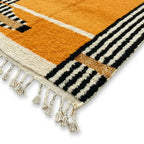 Détail tapis berbère jaune avec franges blanches et bordures rayées finition artisanale marocaine élégante