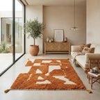 Tapis berbère ocre et écru à motifs abstraits dans un salon lumineux, style bohème chic et décoration moderne