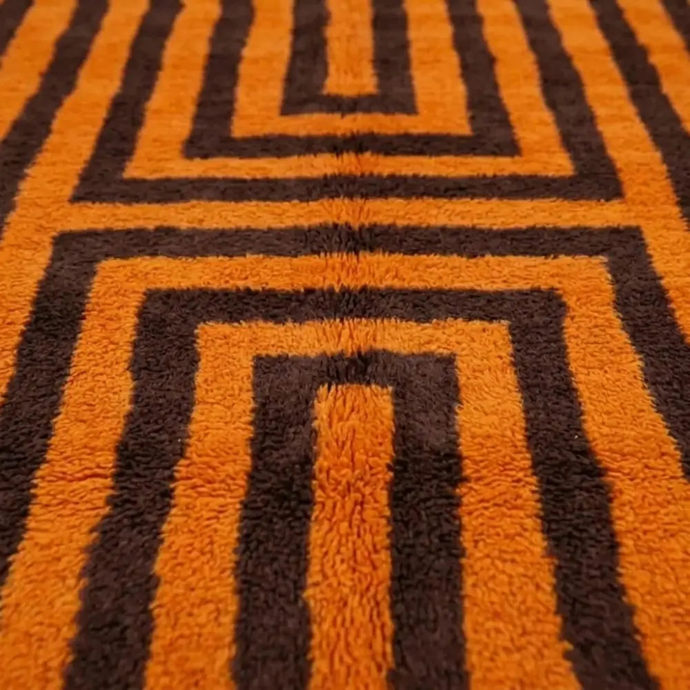 Gros plan sur tapis berbère motif géométrique orange et marron, finition artisanale et design contemporain
