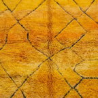 Gros plan sur tapis berbère jaune aux motifs géométriques noirs design artisanal marocain authentique