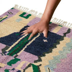 Main appuyant sur tapis berbère multicolore montrant texture moelleuse et confort du tissage