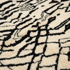 Gros plan tapis berbère noir et blanc motifs abstraits en laine épaisse texture artisanale marocaine