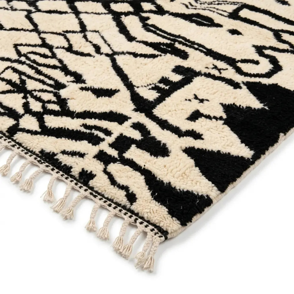 Détail tapis berbère noir et blanc avec franges et motifs abstraits finition artisanale marocaine