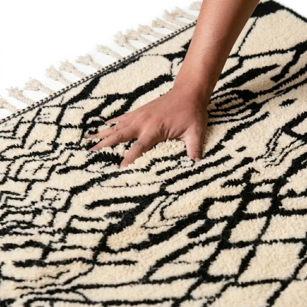 Main appuyant sur tapis berbère noir et blanc texture douce et moelleuse laine artisanale haut de gamme