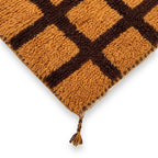 Détail tapis berbère orange avec motifs marron et franges finition artisanale marocaine haut de gamme