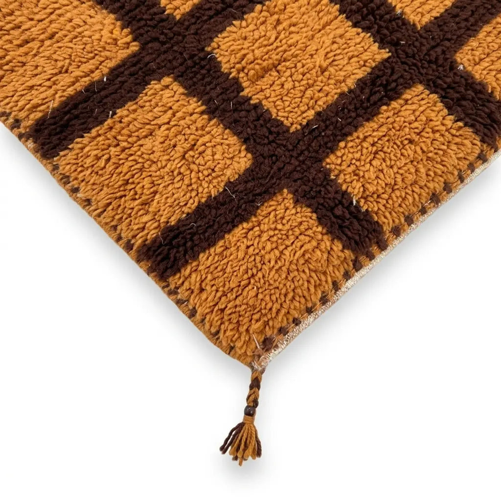 Détail tapis berbère orange avec motifs marron et franges finition artisanale marocaine haut de gamme