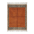 Tapis berbère orange avec centre uni et bordures rayées noir et blanc, style minimaliste et décoration intérieure élégante