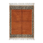 Tapis berbère orange avec centre uni et bordures rayées noir et blanc, style minimaliste et décoration intérieure élégante