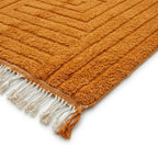 Détail tapis berbère orange avec franges tressées et motif géométrique, design tendance et qualité artisanale