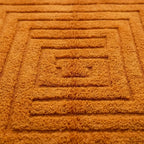 Gros plan tapis berbère orange avec motif géométrique en relief, texture épaisse et artisanale haut de gamme