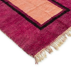 Détail des franges d’un tapis berbère rose fuchsia avec centre pêche, soulignant une finition artisanale haut de gamme et durable